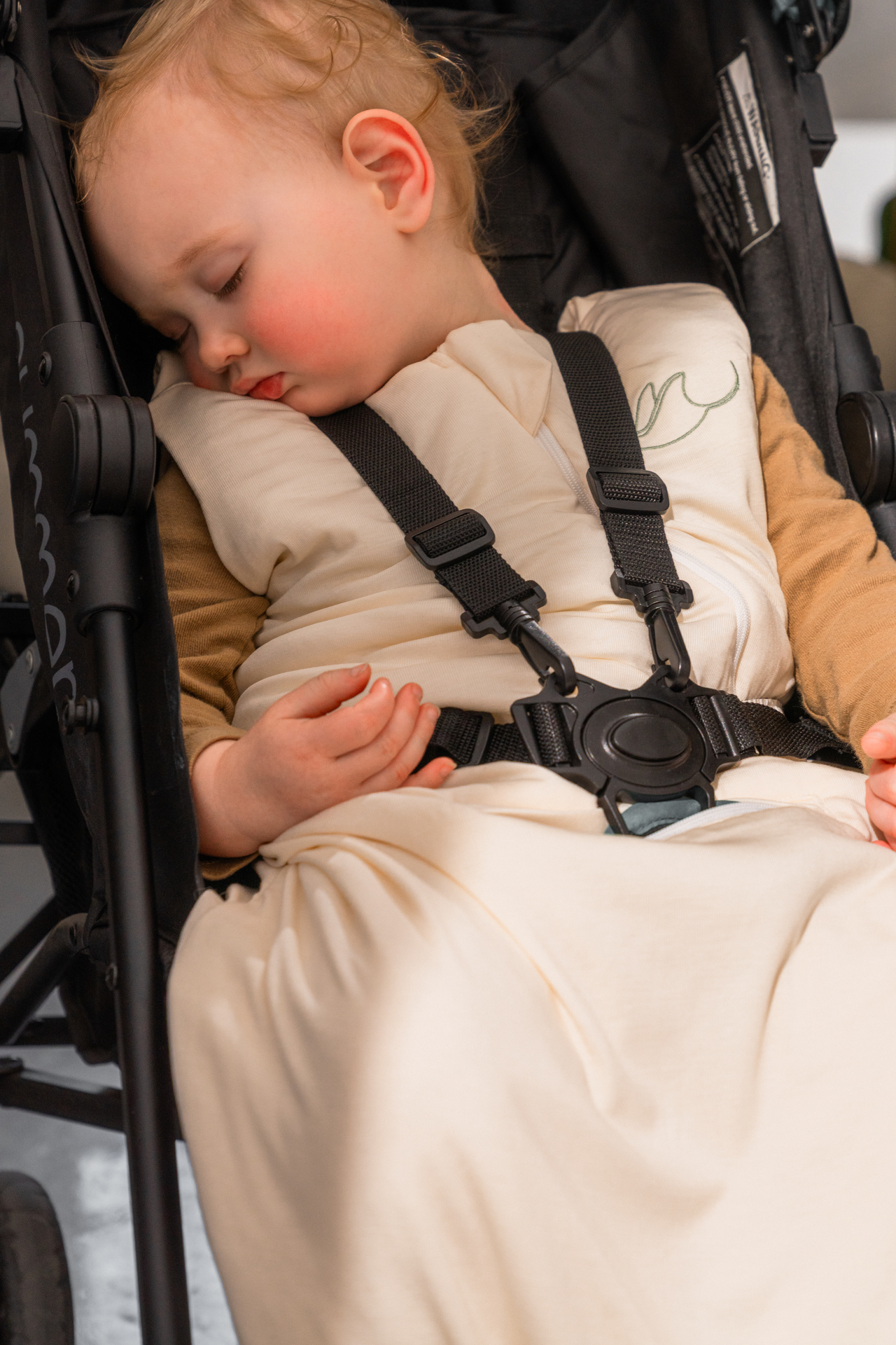 Baby napping in a stroller wearing the Morpheia sleep sack